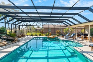 Piscina descoberta coberta com espreguiçadeiras e vista para uma área residencial.