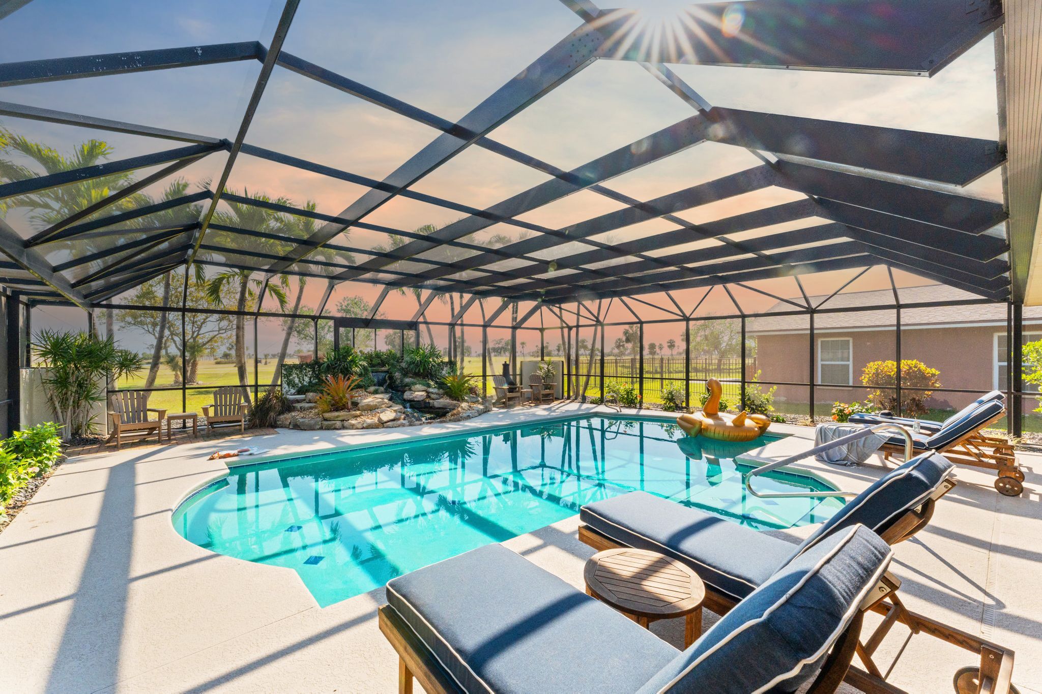 A covered outdoor swimming pool with lounge chairs and a view of the surrounding landscape.