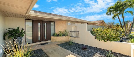 Ein modernes Haus mit Terrasse, Wasserspiel und verschiedenen Pflanzen.