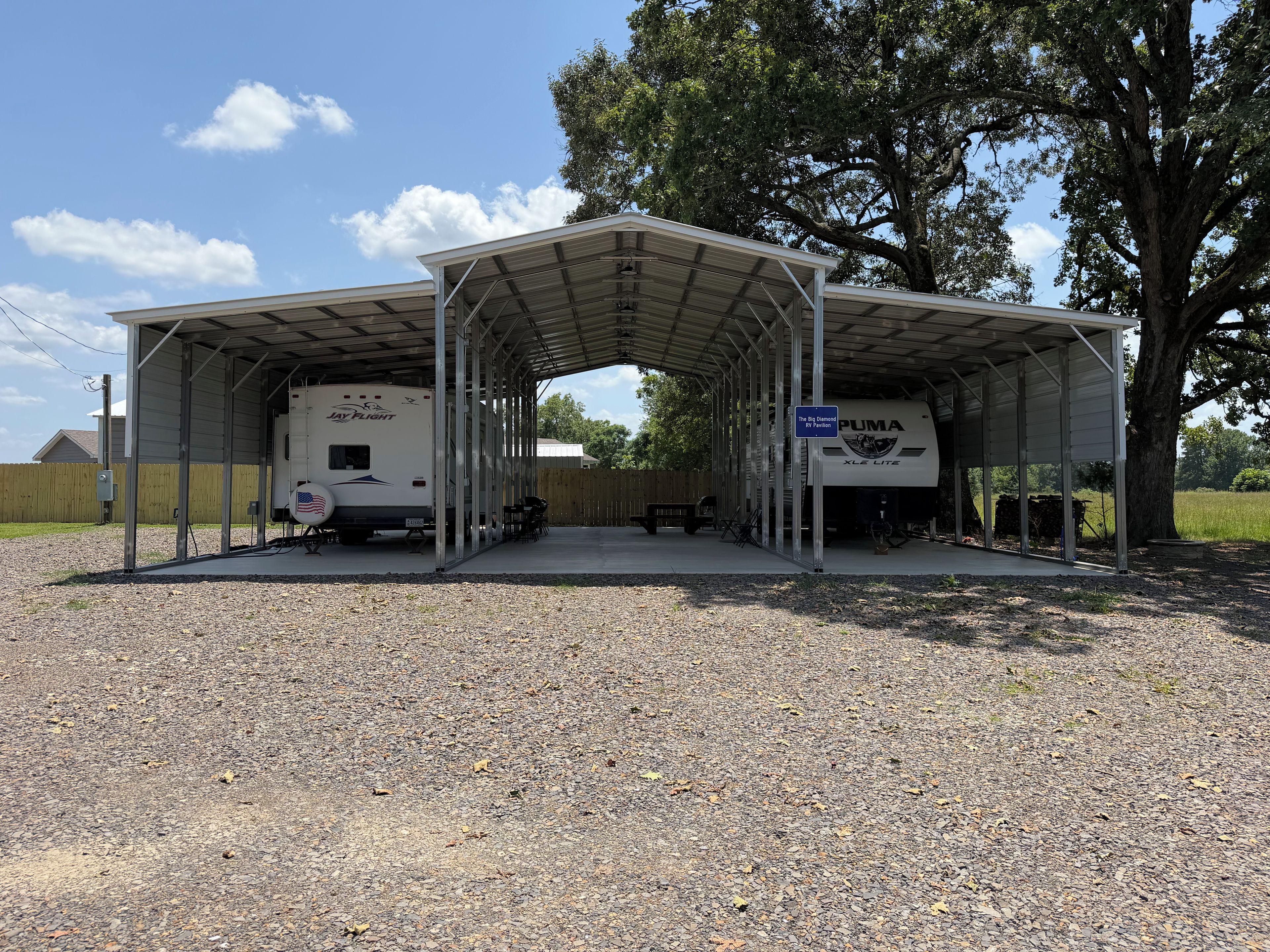 A covered parking area with two RVs, a covered picnic table, and a sign for 'The Big Diamond of Portions.'