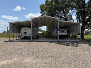 A covered parking area with two RVs, a covered picnic table, and a sign for 'The Big Diamond of Portions.' - Cozy 1-bedroom recreational vehicle in perfect Delight with AC (Delight)