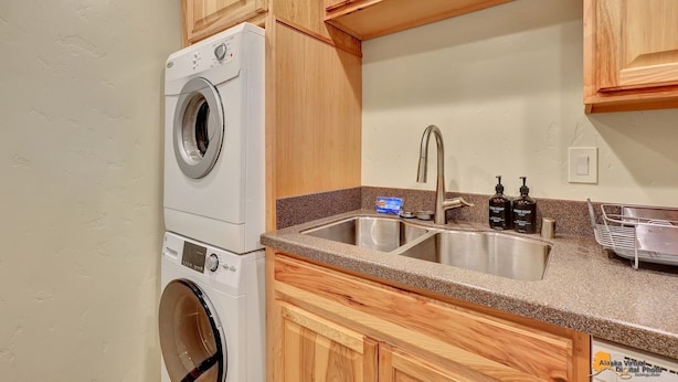 Een compacte keuken met houten kastjes, een inbouw wasmachine en een dubbele spoelbak.