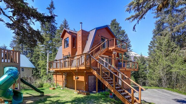 Eine Holzhütte mit einer Terrasse und einer Treppe, die zu einer zweiten Ebene führt.