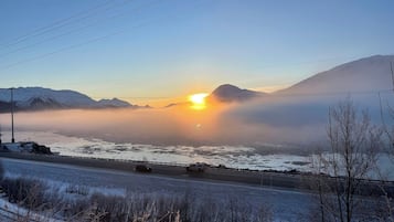 A road with a view of mountains and a sunset.