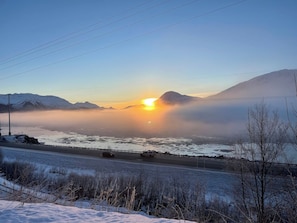 A road with a view of mountains and a sunset.