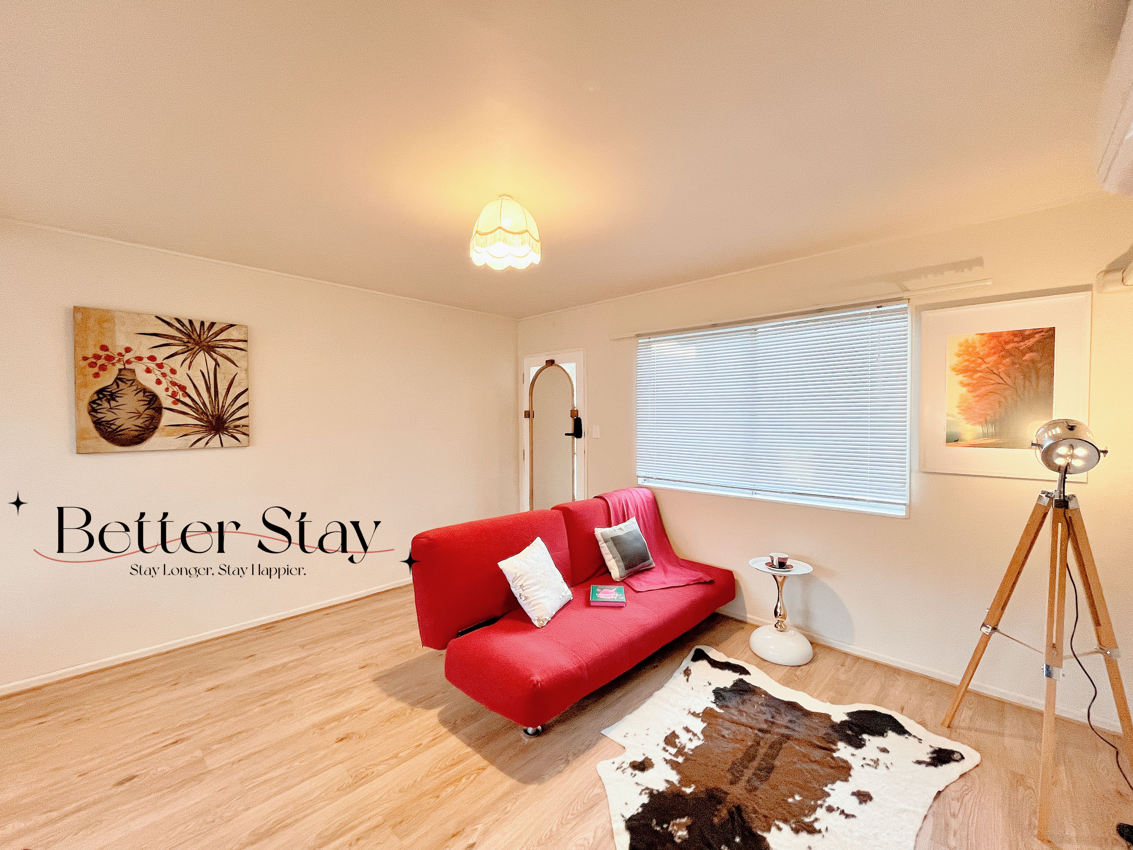 A room with a red sofa, a cowhide rug, a lamp, and artwork on the walls.