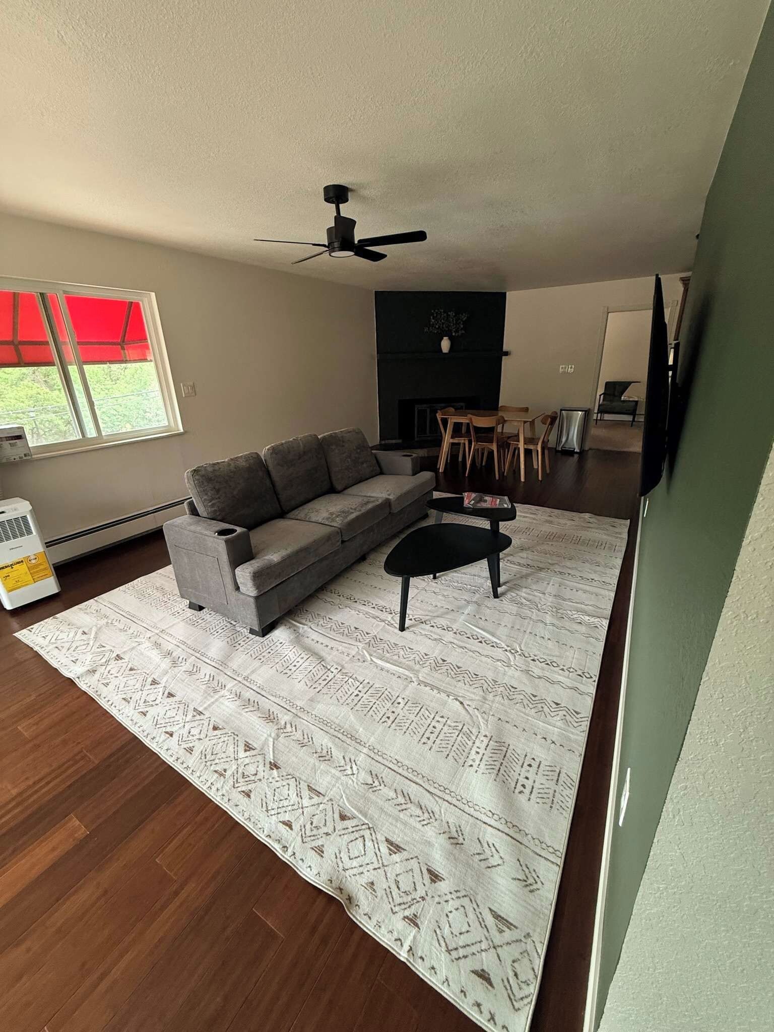 A living room with a gray sofa, a black coffee table, and a patterned rug.