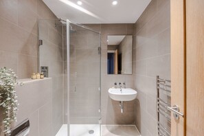 A modern bathroom with a glass shower enclosure, a white sink, and a mirror. - The Eyre Suite Seven - Farringdon - by Frankie (London)