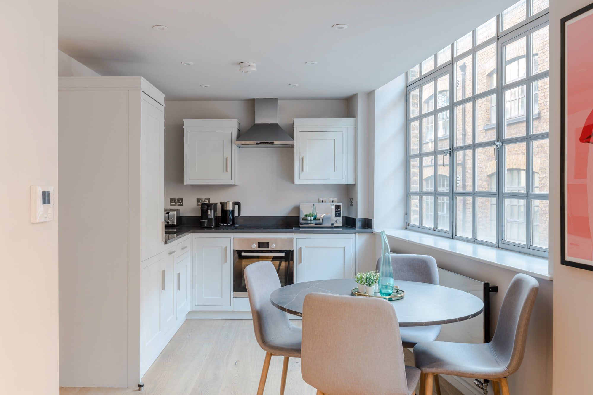 A modern kitchen with white cabinets, a black countertop, and a dining area with a round table and four chairs.
