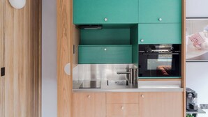 A modern kitchen with teal cabinets, stainless steel appliances, and a wooden accent wall. - The Italian Collection - Soho - by Frankie (London)
