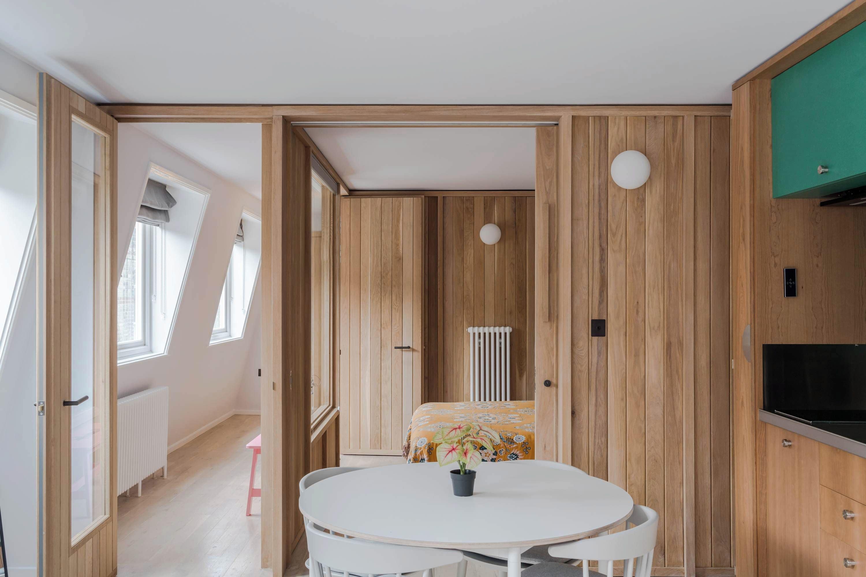A room with a round table, a radiator, and wooden paneling.