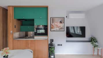 Een moderne keuken met groene kastjes, een inbouwoven en een koffieapparaat.