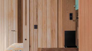 Een kamer met een houten garderobe, een bed met bloemenbedekking en een ronde tafel met stoelen.