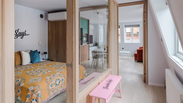 A bedroom with a bed, a bench, a mirror, and a view into another room. - The Italian Collection - Soho - by Frankie (London)