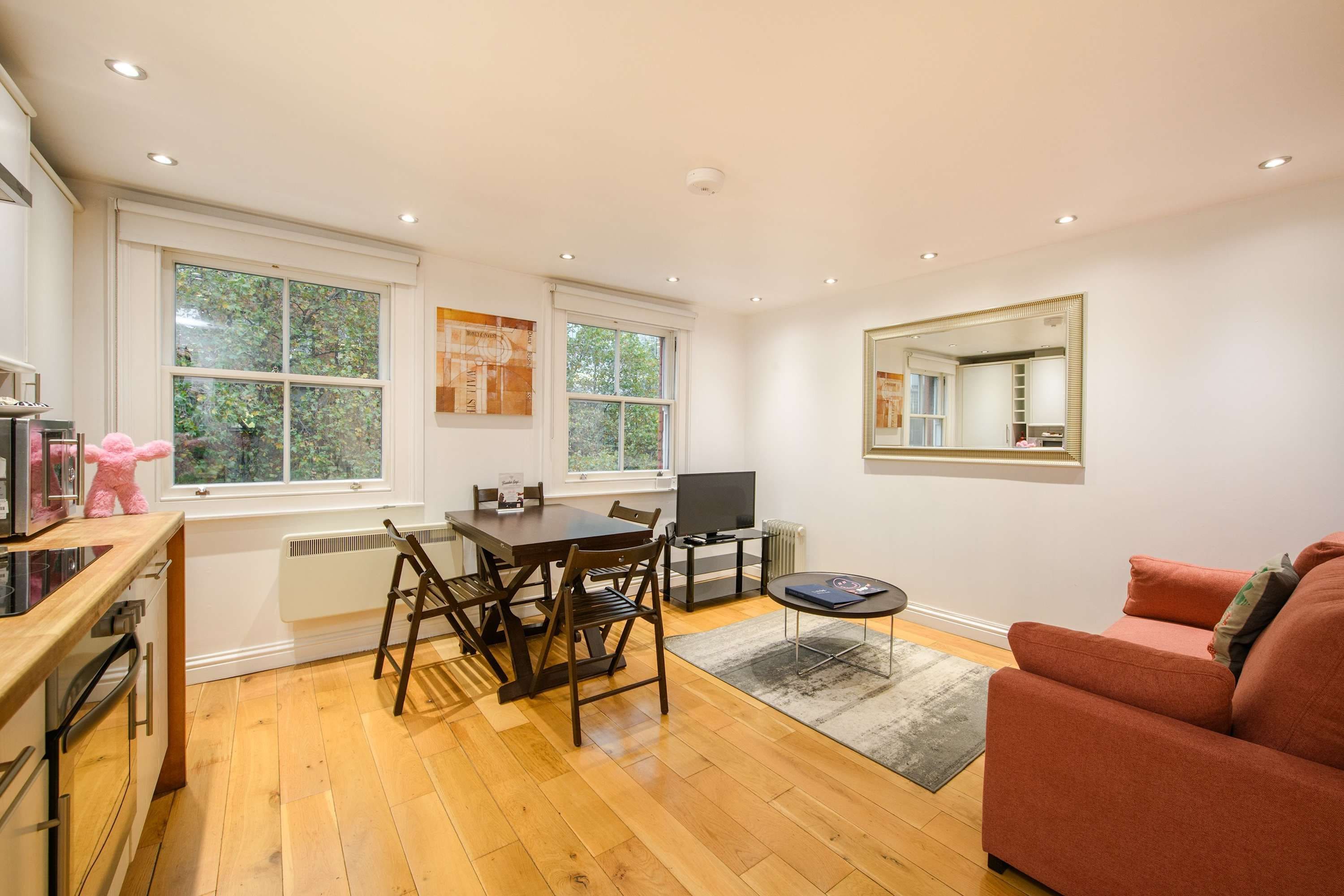 A modern kitchen with a dining area, a TV, and a large window.