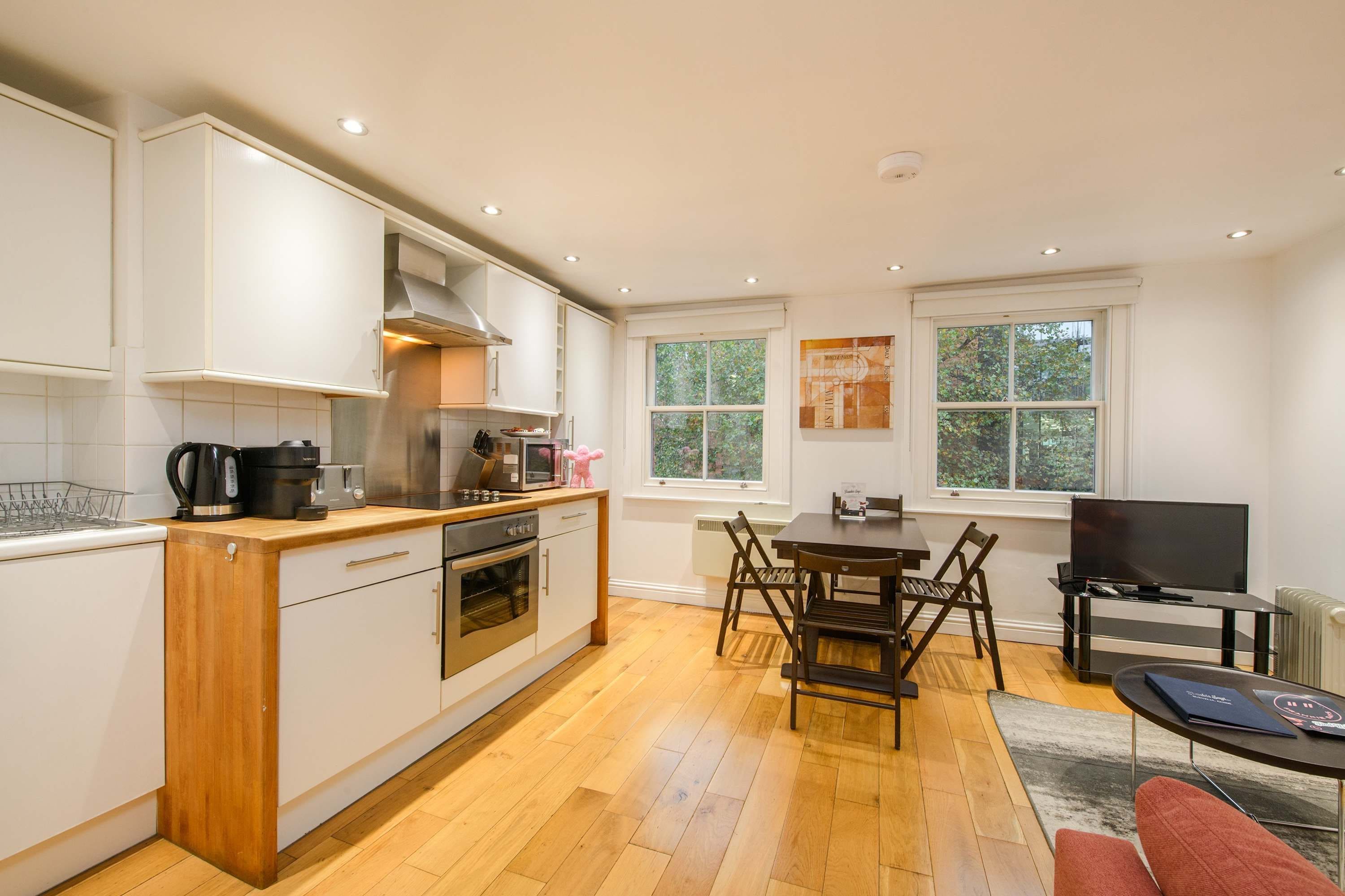 Una cocina moderna con armarios blancos, encimera de madera y un comedor con mesa y sillas.