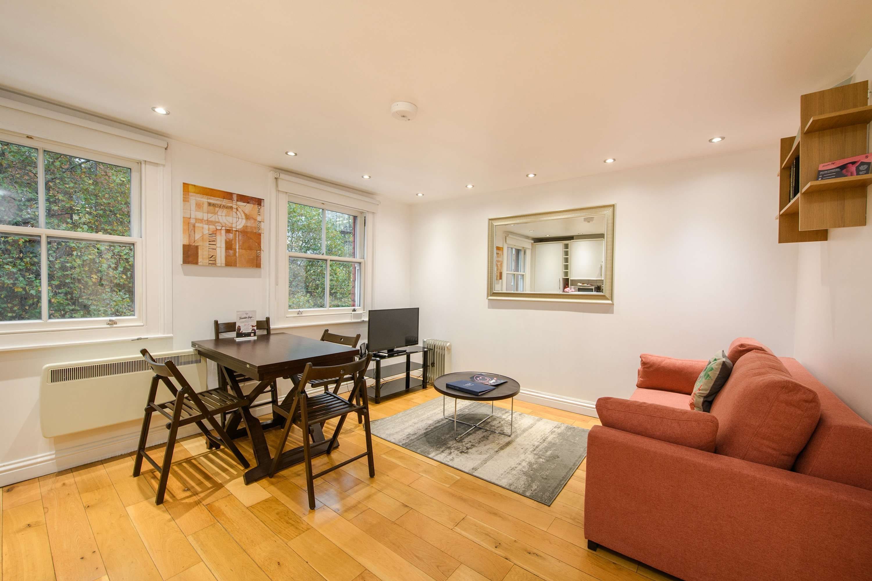 A living room with a dining table, chairs, a sofa, a TV, and a fireplace.