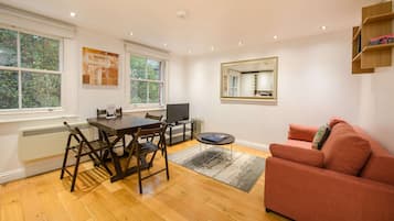 A living room with a dining table, chairs, a sofa, a TV, and a fireplace.