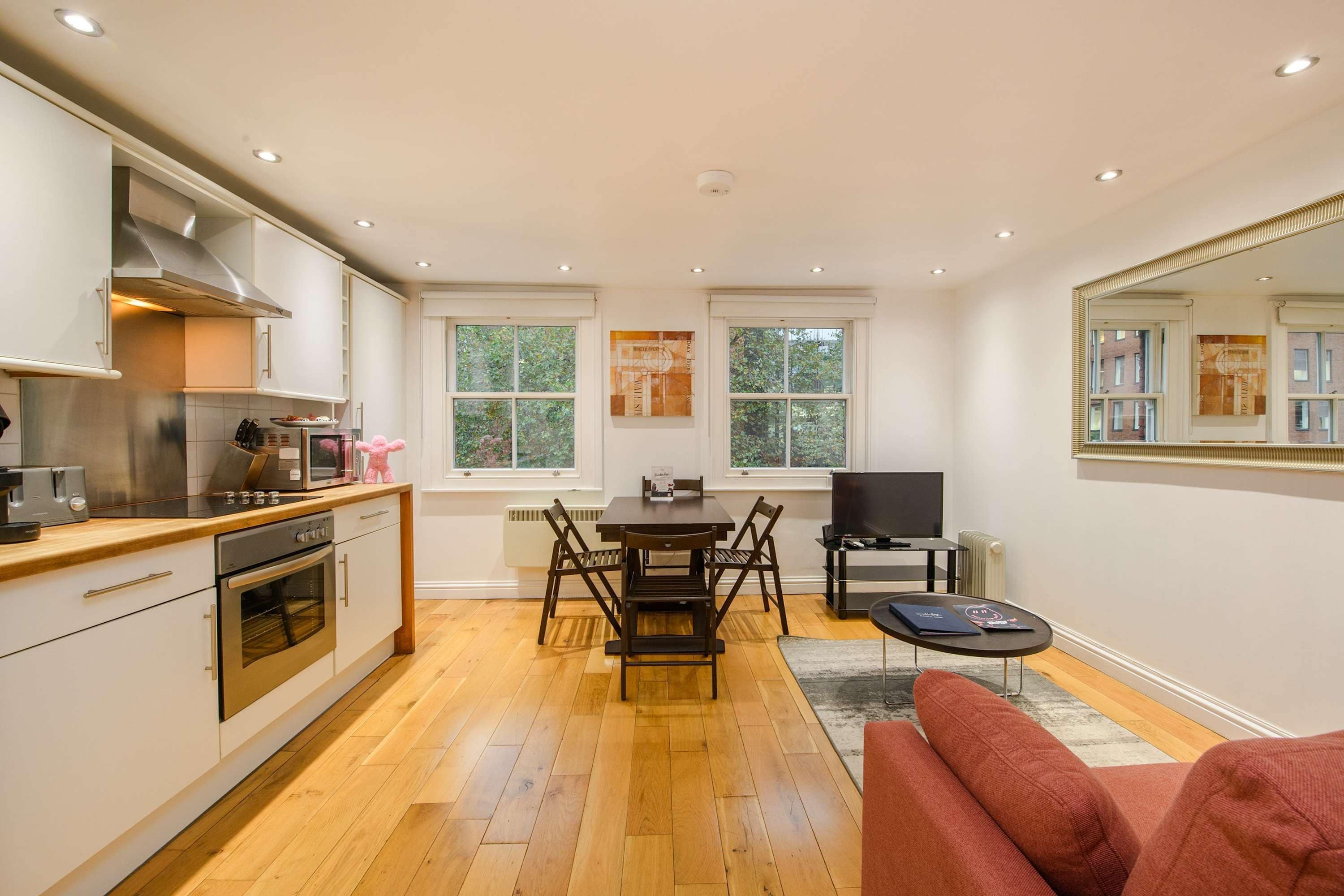 A modern kitchen with a dining area, a TV, and a sofa.
