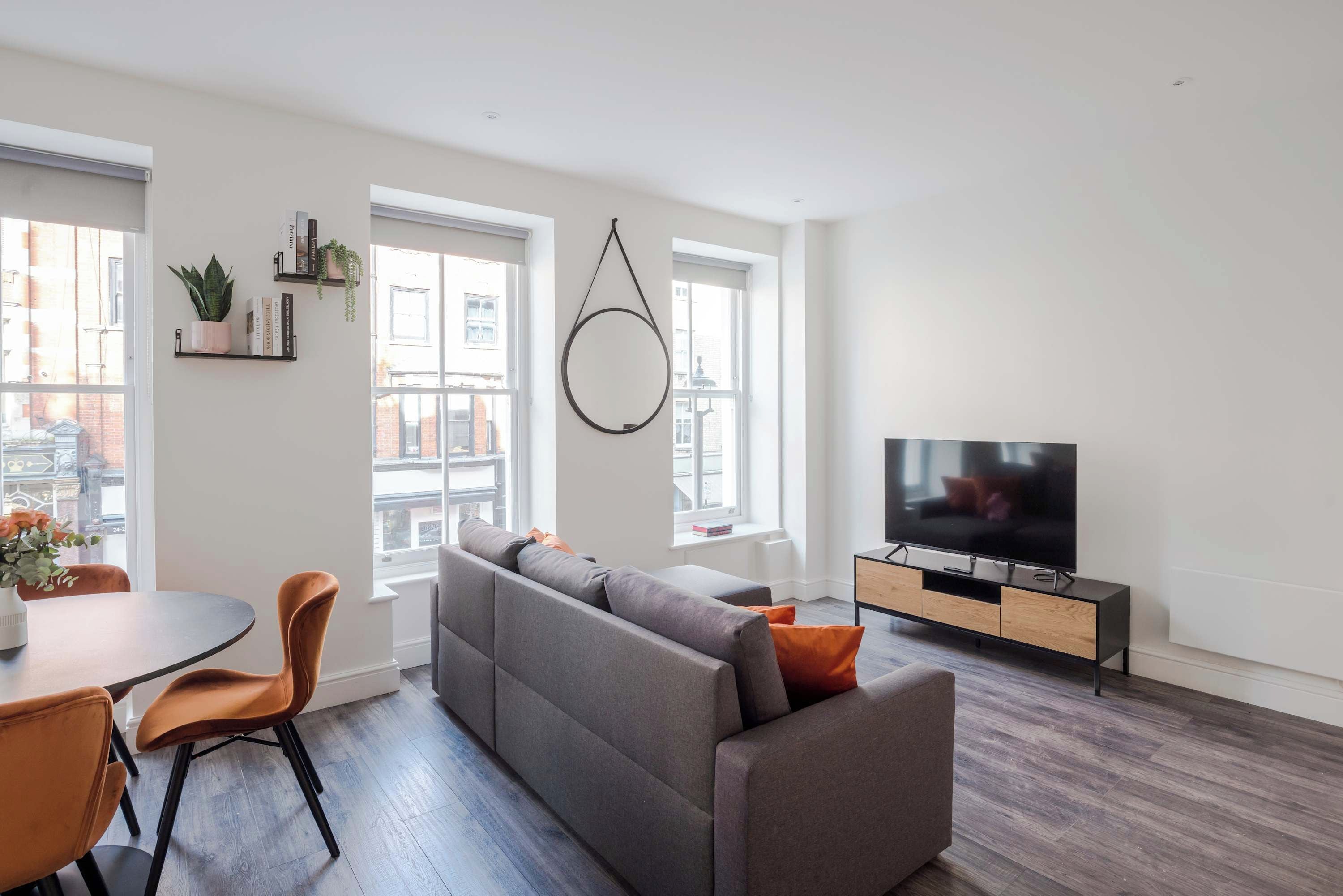 Un salon moderne avec un canapé, un téléviseur et un coin repas.