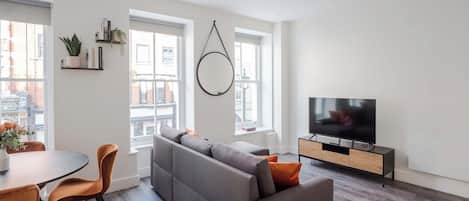 Un salon moderne avec un canapé, un téléviseur et un coin repas.