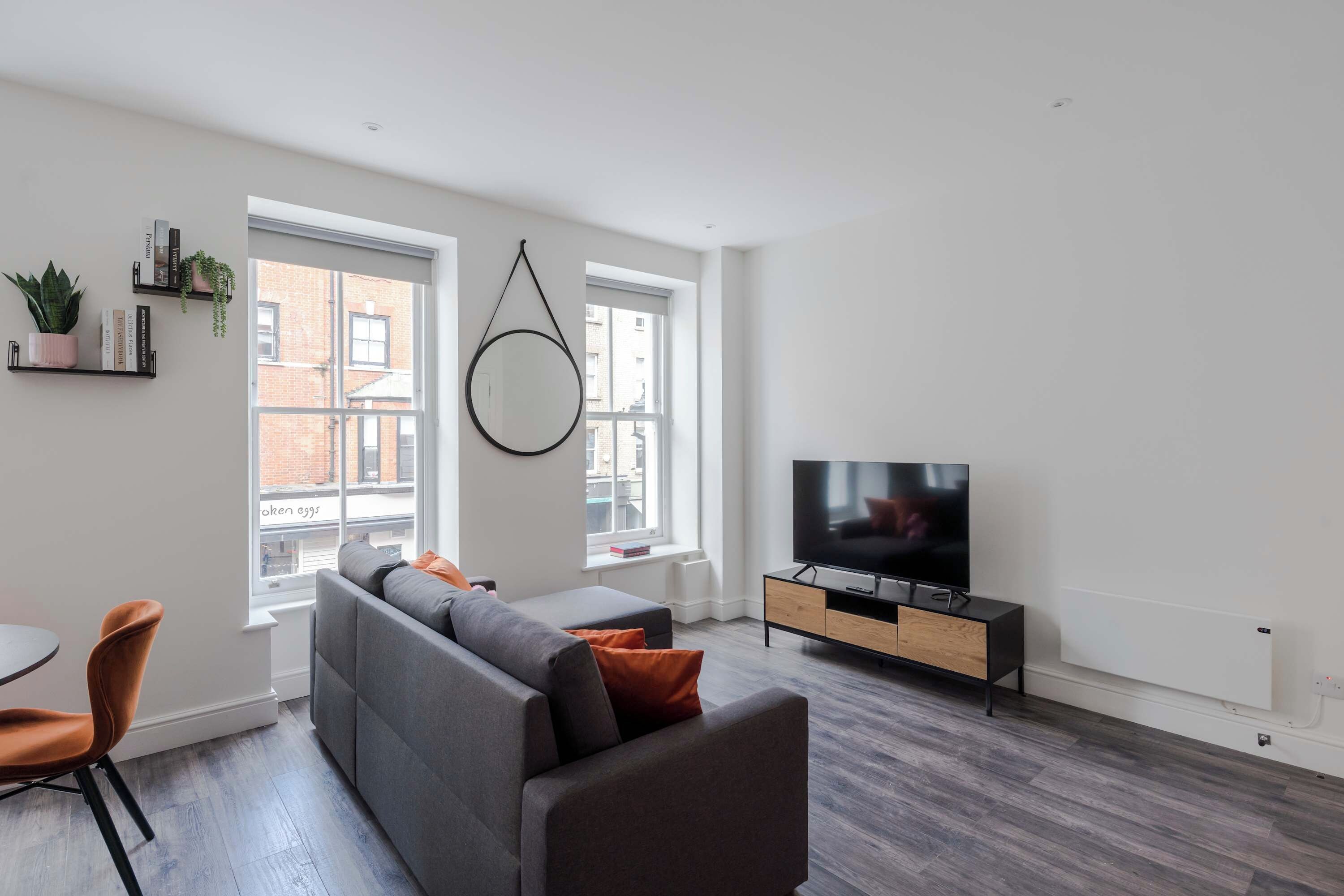 A modern living room with a sofa, TV, and dining area.