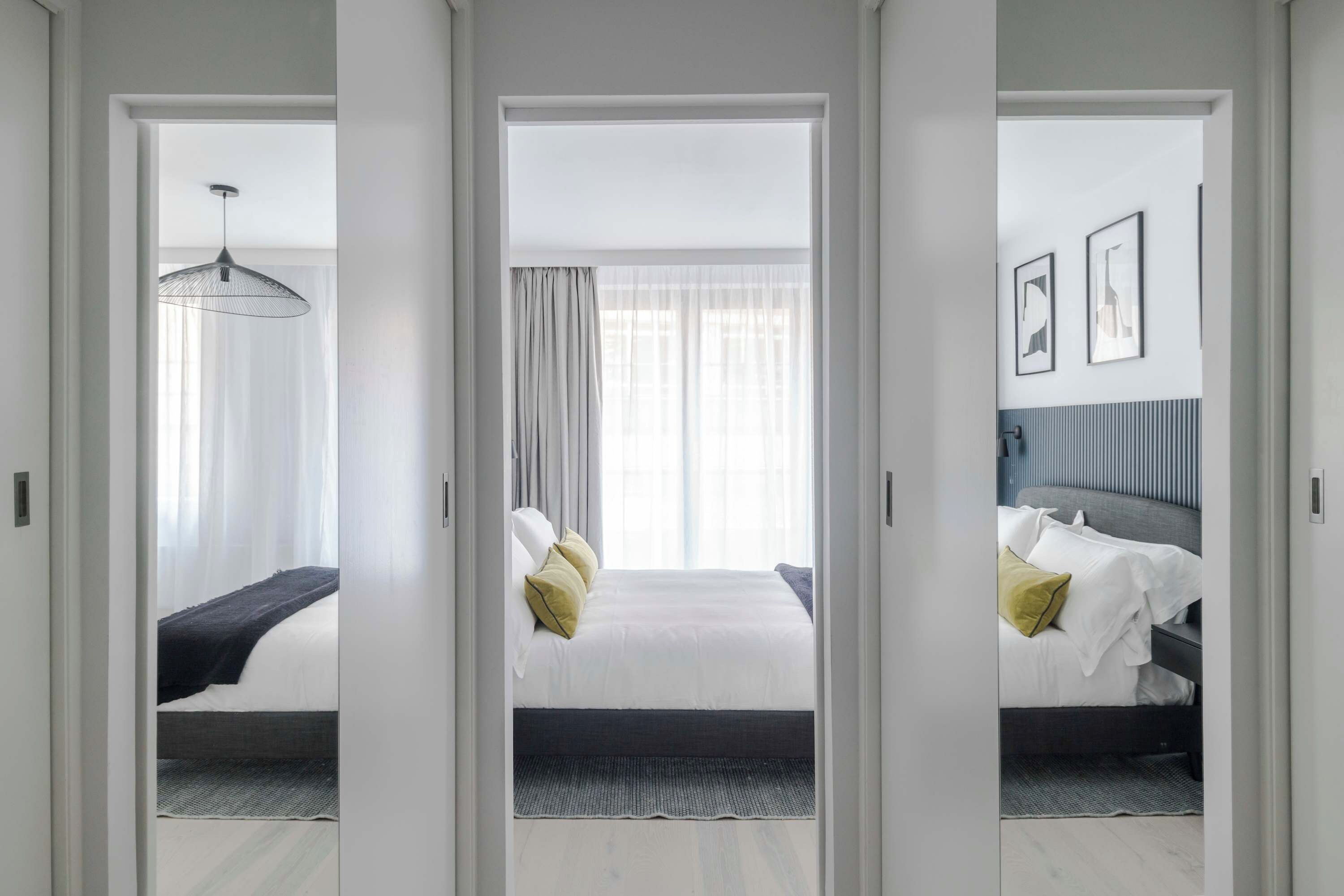 Hotelkamer met een bed, nachtkastje, lamp en raam met gordijnen.
