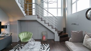 Un interior moderno con una escalera, un sillón verde, una mesa de centro redonda y un sofá.