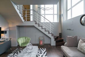 Ein modernes Interieur mit einer Treppe, einem grünen Sessel, einem runden Couchtisch und einem Sofa.
