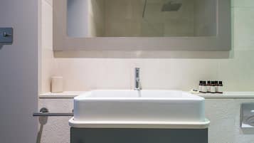 Ein Badezimmer mit einem weißen Waschbecken, einem Spiegel darüber und einem Ablagefach mit Toilettenartikeln.