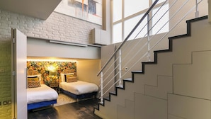 Ein modernes Interieur mit Treppe, einem Schlafzimmer im Zwischengeschoss mit schrägem Dach und einer Ziegelwand.