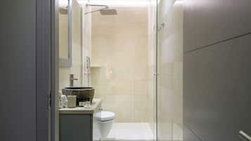 A modern bathroom with a glass shower enclosure, a toilet, and a sink with a marble basin.