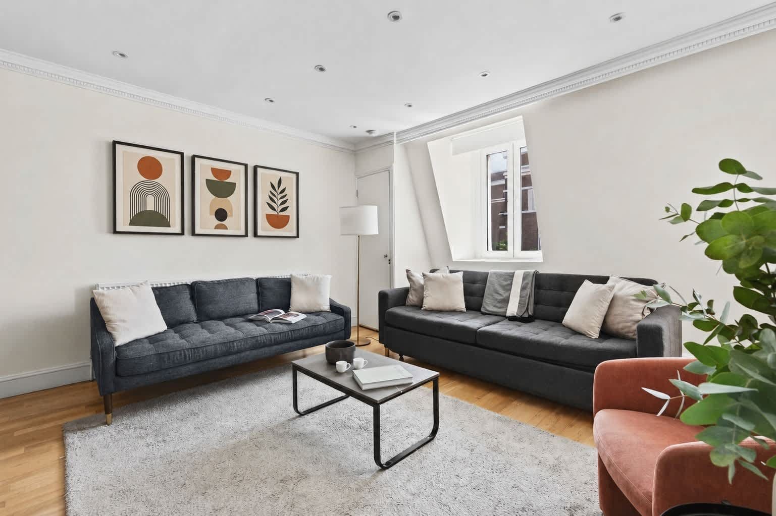 Un salon moderne avec deux canapés, une table basse et des œuvres d’art encadrées accrochées au mur.