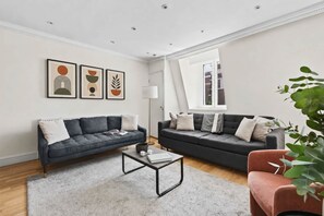 Un salon moderne avec deux canapés, une table basse et des œuvres d’art encadrées accrochées au mur.