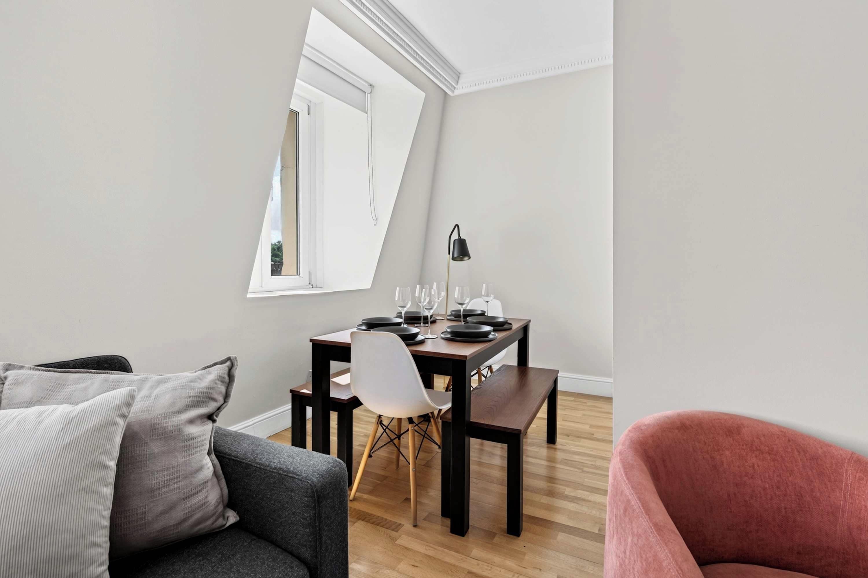 Uma sala de estar moderna com área de jantar, um sofá, uma poltrona e uma mesa posta para refeição.