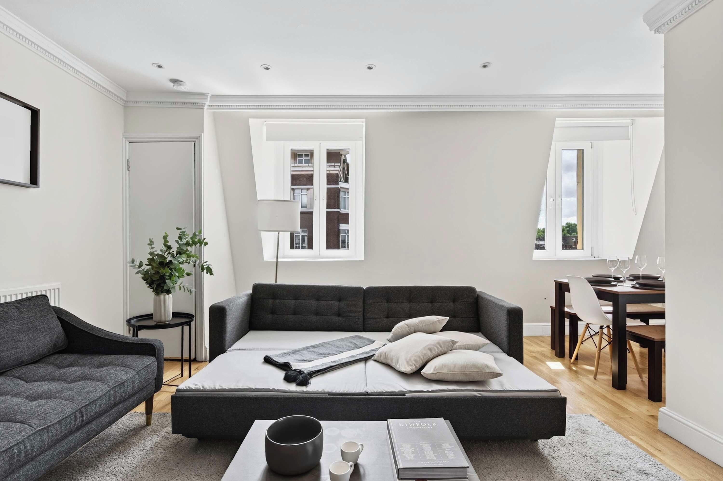 A modern living room with a sofa, a coffee table, and a dining area with a table and chairs.