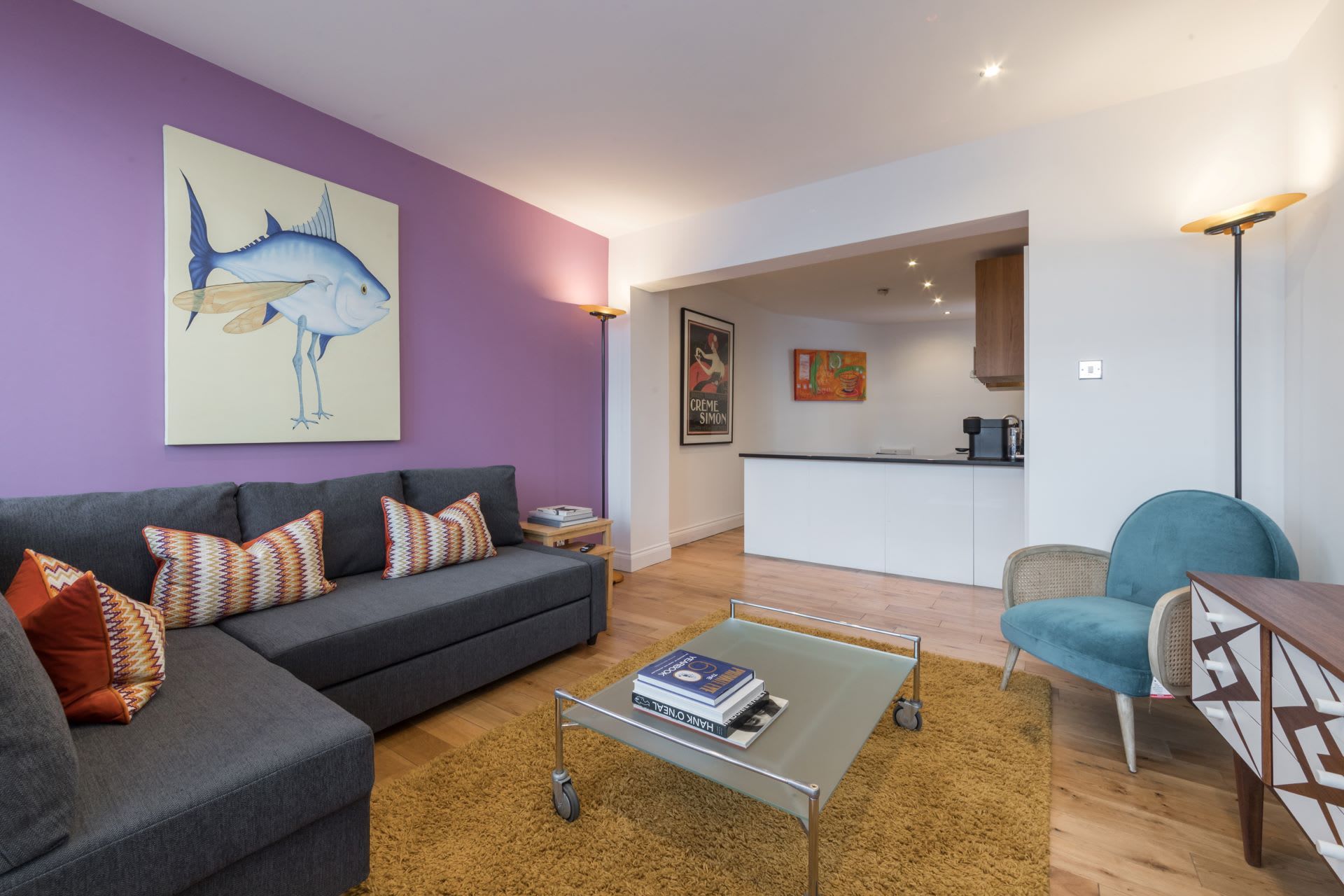 A modern living room with a grey sofa, a coffee table, and a blue armchair.