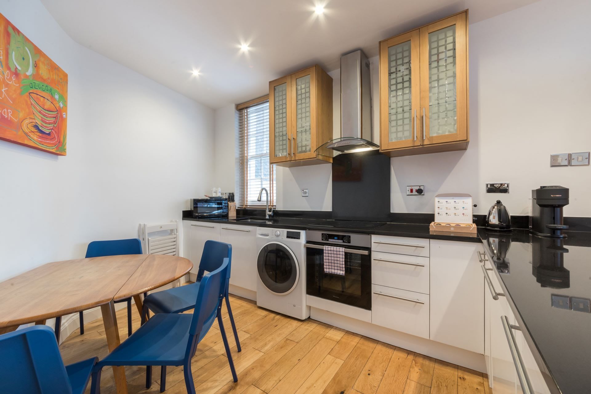 A compact kitchen with a washing machine, a stove, and a coffee maker.