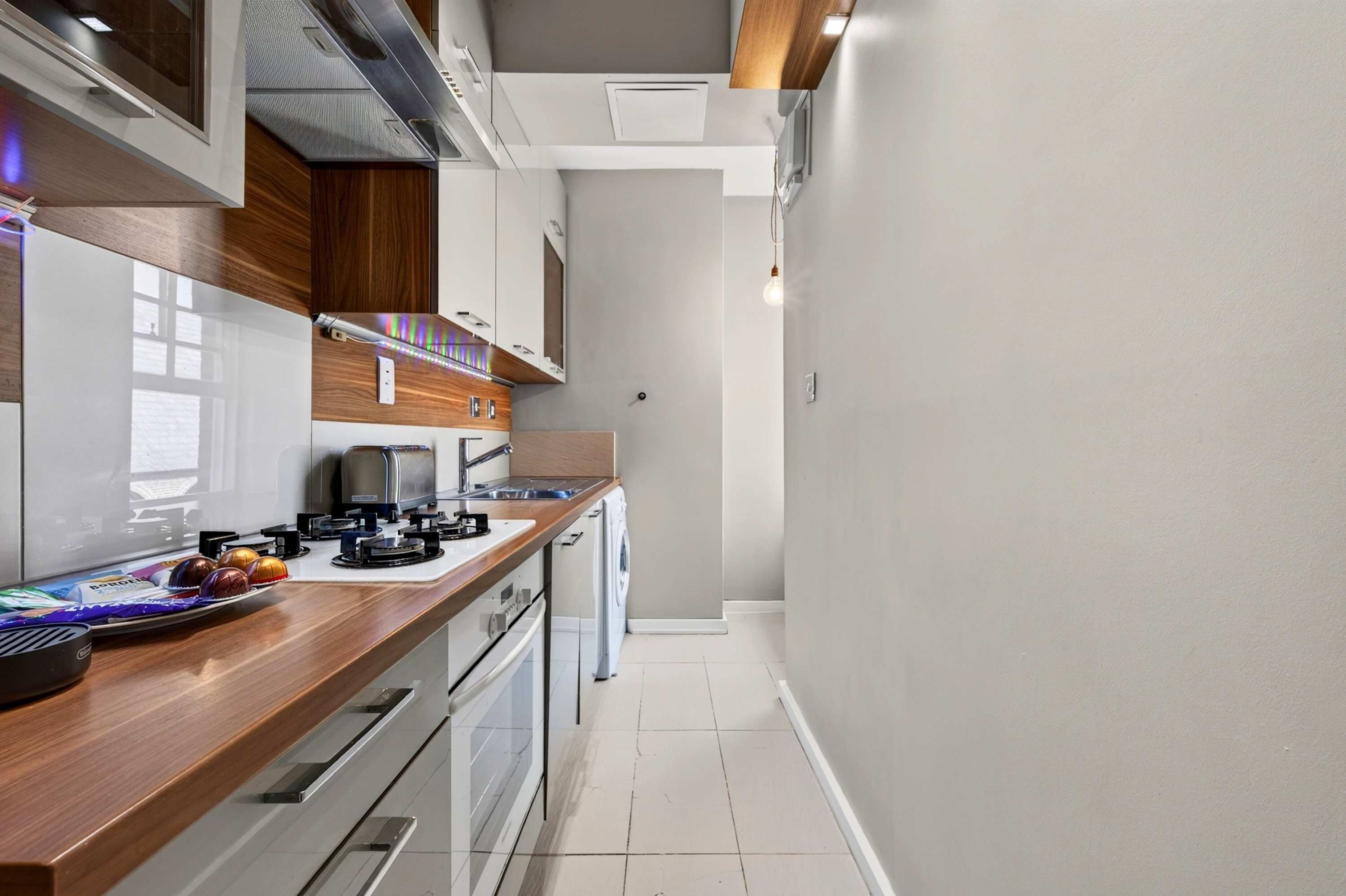Une cuisine moderne dotée d’un plan de travail en bois, d’appareils électroménagers en acier inoxydable et d’un four encastré.