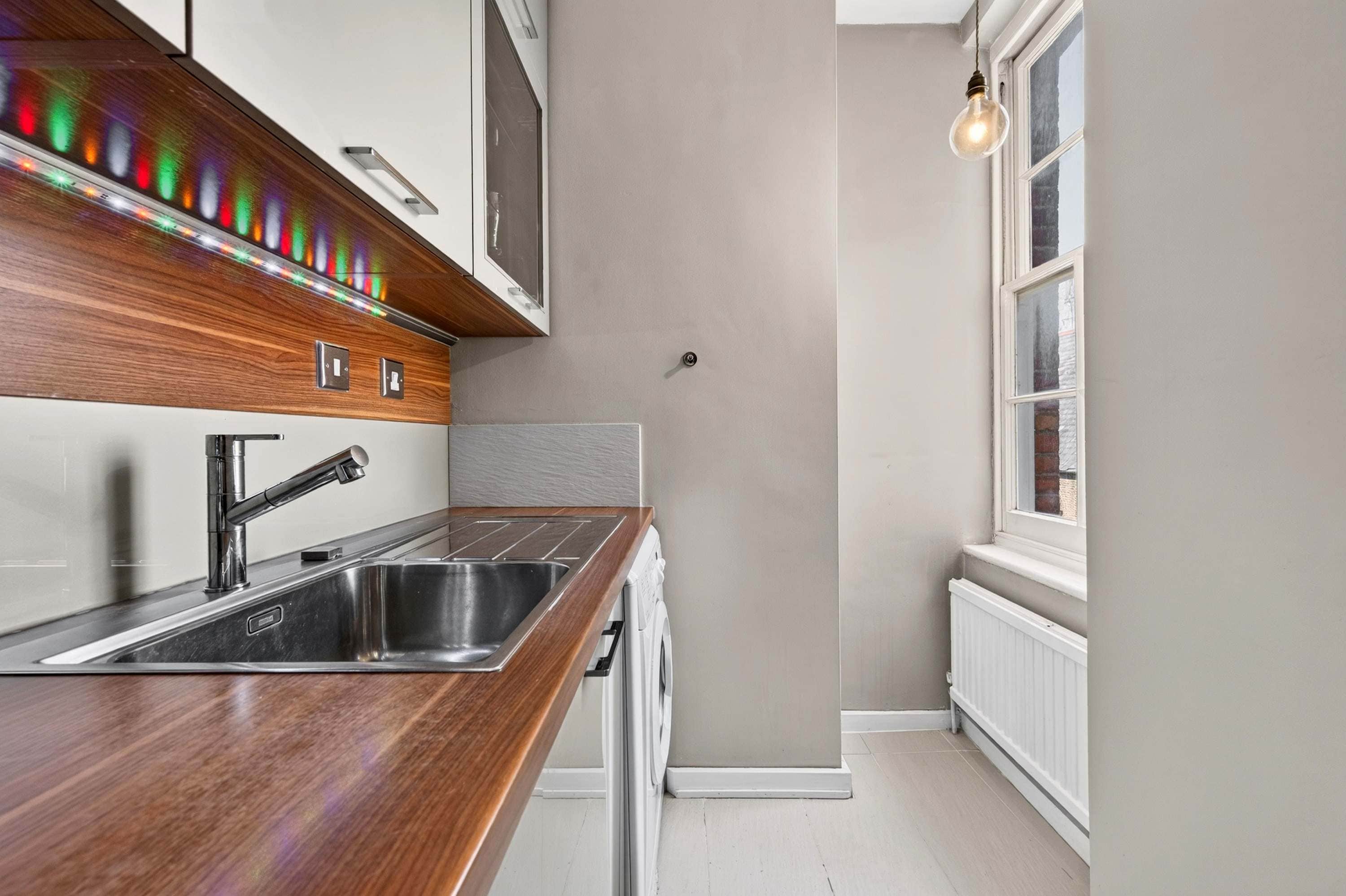 A modern kitchen with a wooden countertop, stainless steel sink, and a built-in washing machine.