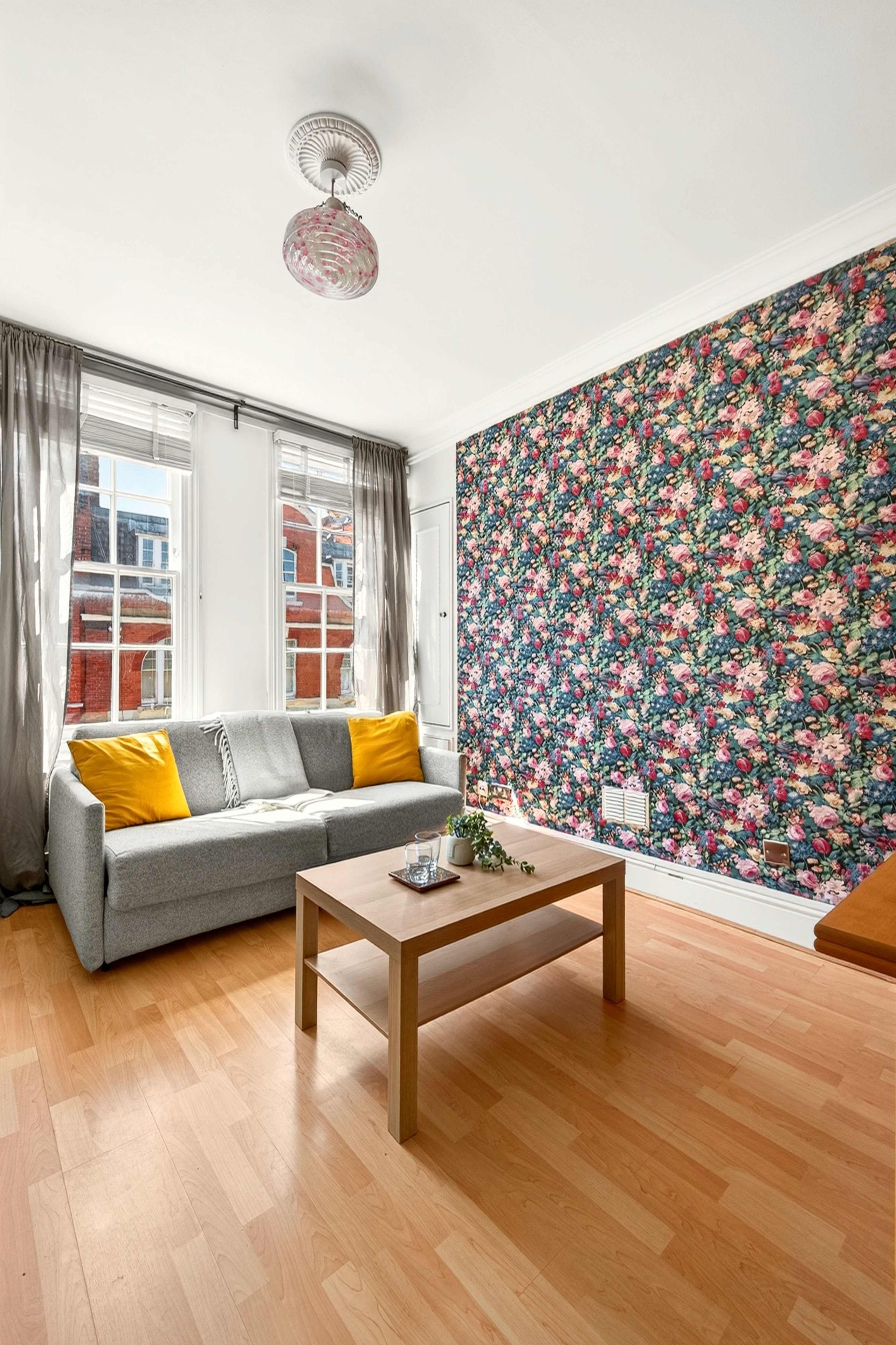 A living room with a sofa, a table, and a floral wallpaper.