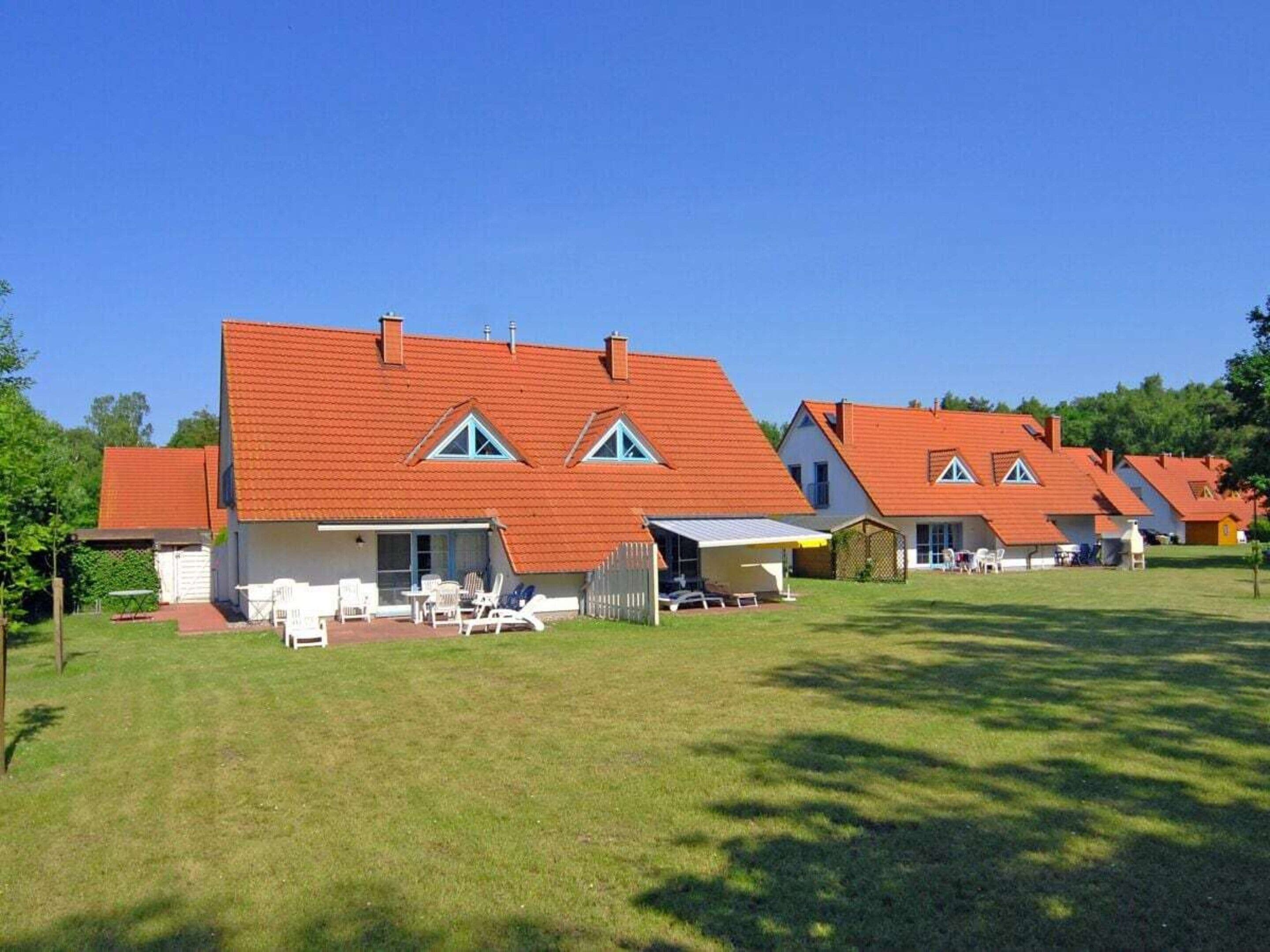 A row of houses with red roofs and white walls, each with a small porch and outdoor seating.