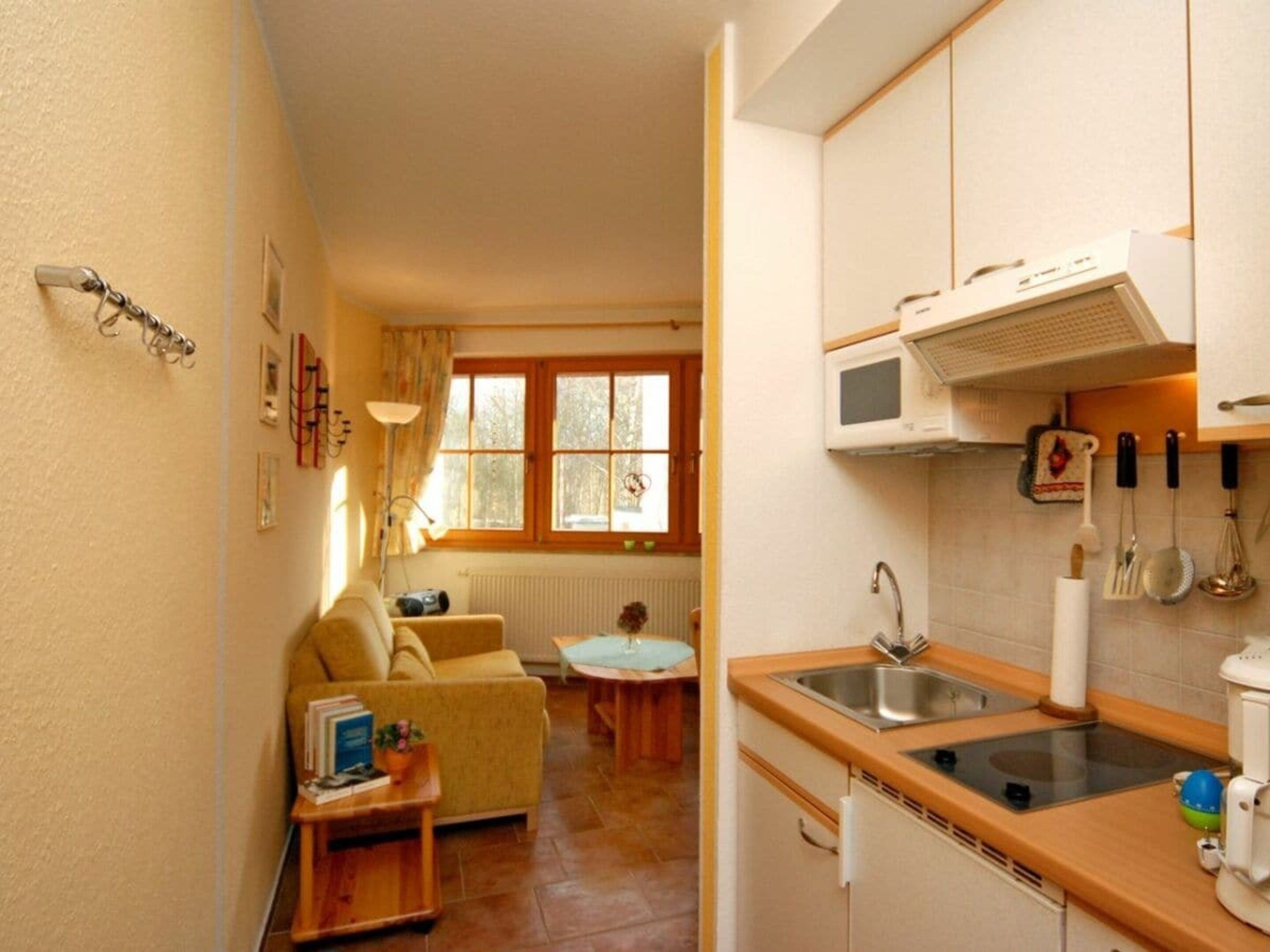 A compact kitchen with a sink, microwave, and basic appliances. A dining area with a table and chairs is visible in the background.