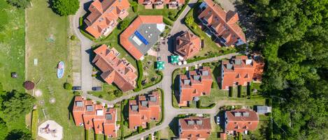 Vista aérea de una zona residencial con varias casas, céspedes verdes y un parque infantil.