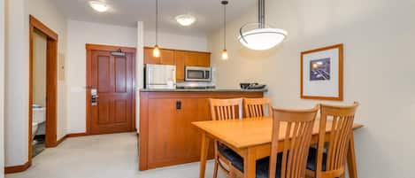Cocina compacta con armarios de madera, una isla central y una zona de comedor con mesa y sillas.