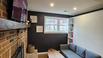 A modern living room with a fireplace, a flat-screen TV, a grey sofa, and a wooden coffee table.