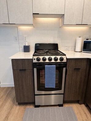 A kitchen with a Danby stove, a microwave, and wooden cabinets. - Midtown Gem Near Downtown (Detroit)