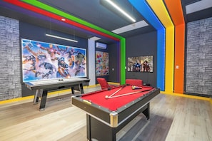 Ein Billardtisch mit roter Spielvliesbahn, umgeben von Wänden mit farbigem LED-Beleuchtung.