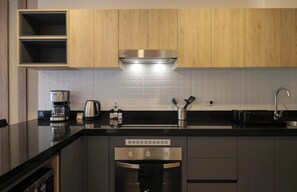 A modern kitchen with wooden cabinets, a stainless steel range hood, a coffee maker, a kettle, and a dishwasher. - w* | Charming Loft w/ Balcony in Prime Miraflores (Miraflores)