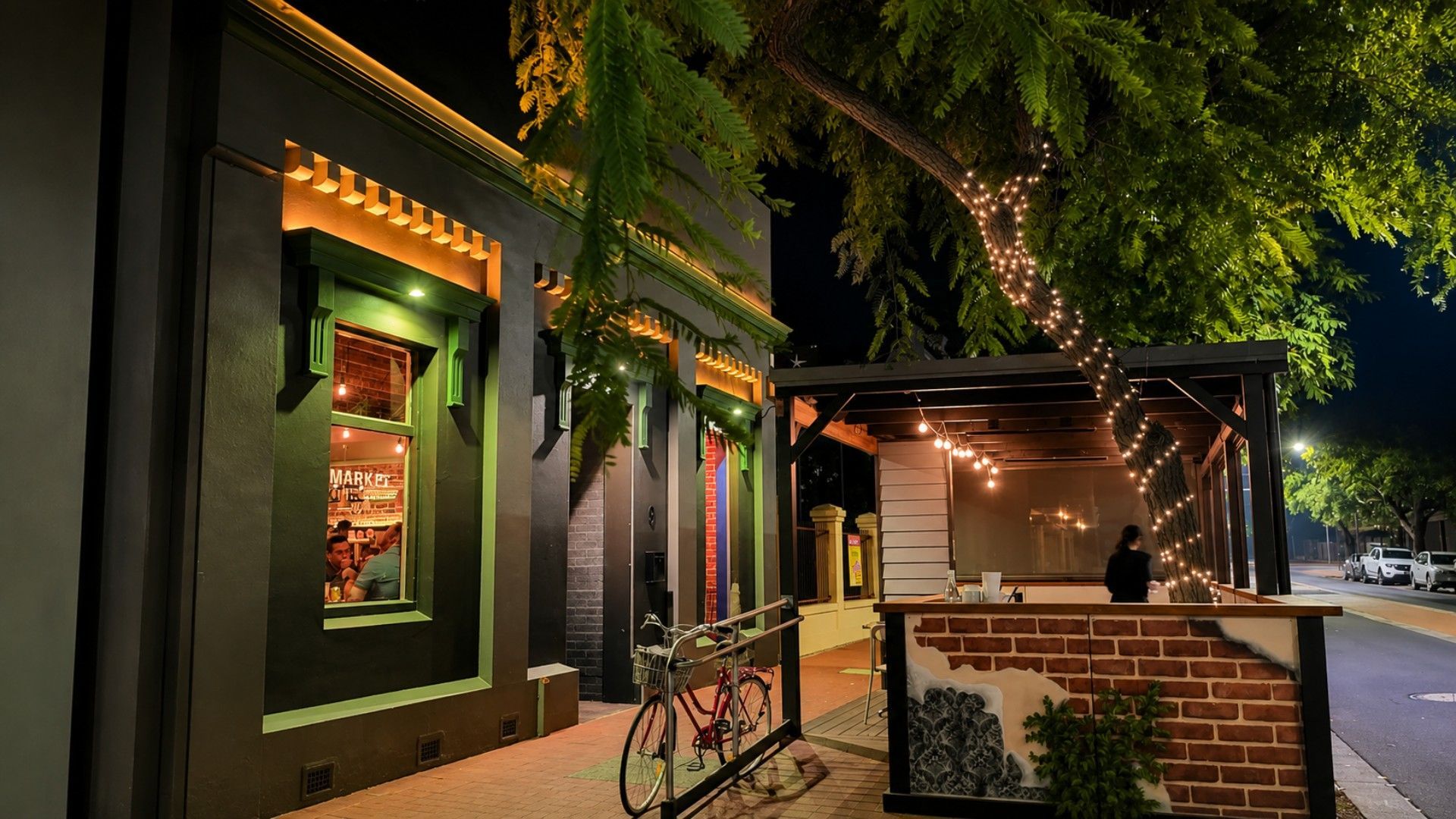 A building with a green facade, a visible entrance, and a bicycle parked outside.